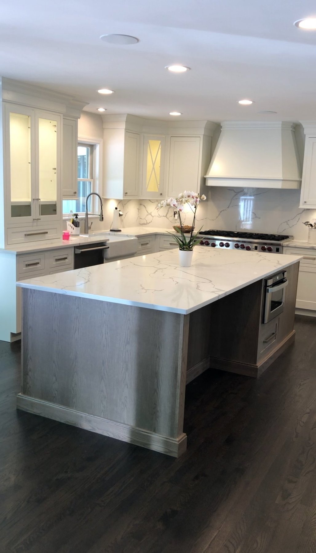 Custom kitchen renovation with gray-stained oak island and calacatta quartz countertops