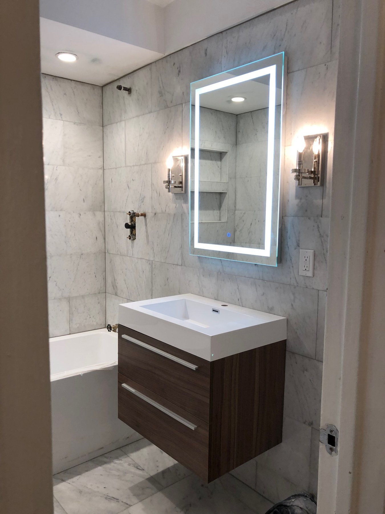 Master bathroom with carrara marble walls and walnut floating vanity