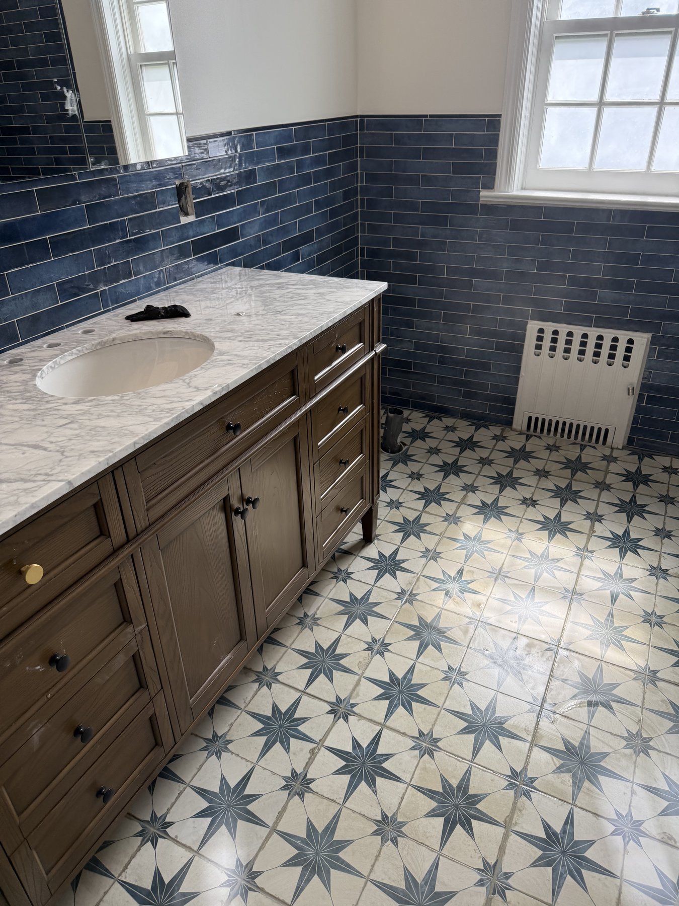 Designer bathroom with blue glazed subway tile and encaustic star floor